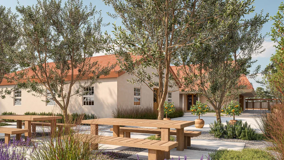 Rendering of wooden picnic tables among olive trees and potted citrus trees in front of a cream stucco church building with a red tile roof.