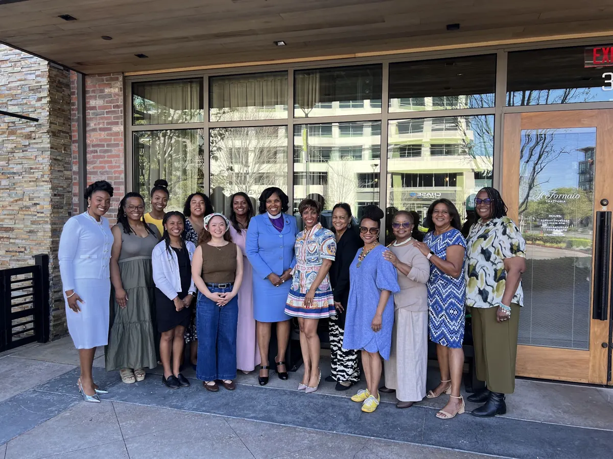 A group of women across generations smiles together outside a restaurant.