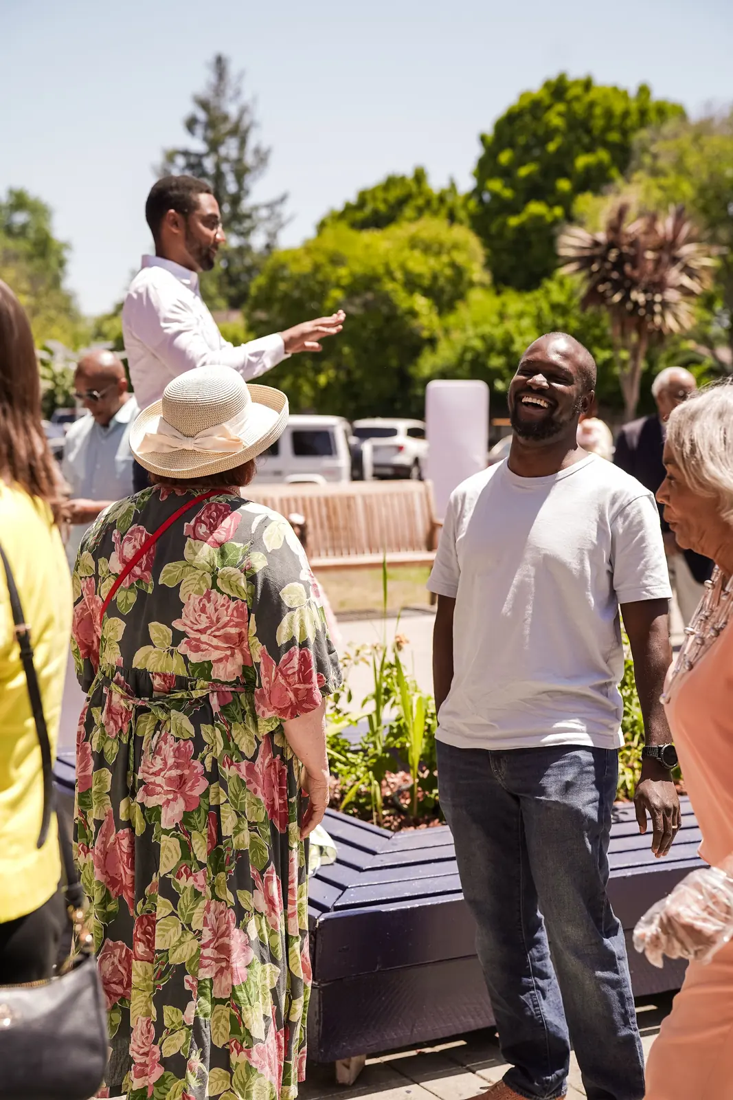 People smile and share conversation together in the sunny church courtyard.