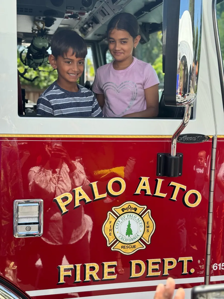 Two children smile from the cab of a Palo Alto Fire Department truck.