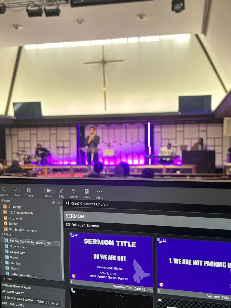A computer screen displays presentation slides with the sanctuary stage visible beyond it.