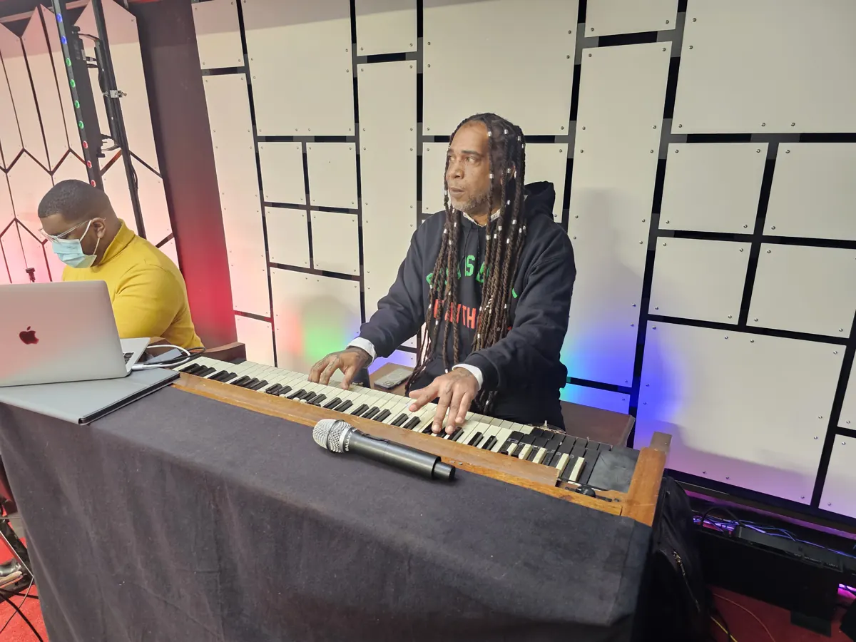 A person plays an electronic keyboard beside a laptop during worship.