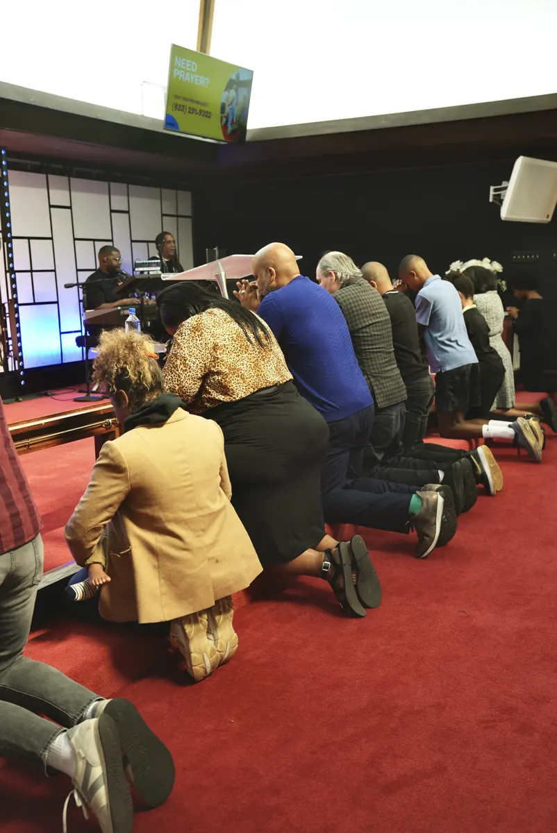 People kneel side by side at the red-carpeted altar rail in the sanctuary.