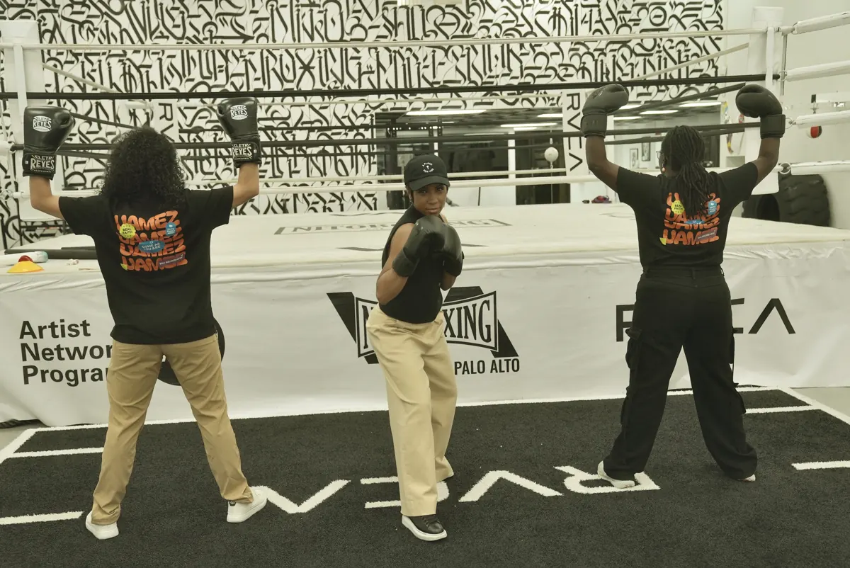 Three people dance together in front of a boxing ring at the church relaunch party.